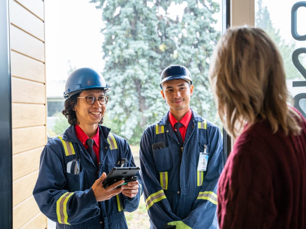 Smiling furnace cleaning technicians greeting a customer at her door