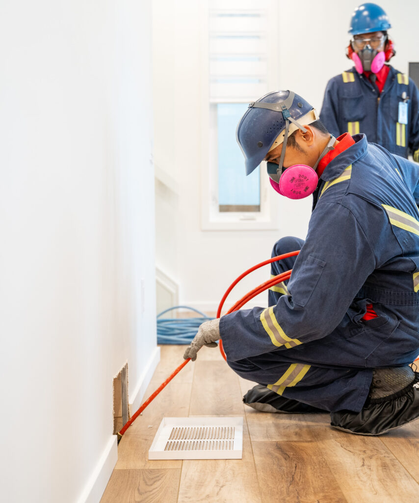 An Alberta Furnace Cleaning technician in a clean, sharp uniform cleaning the ducts of a customers' home. 