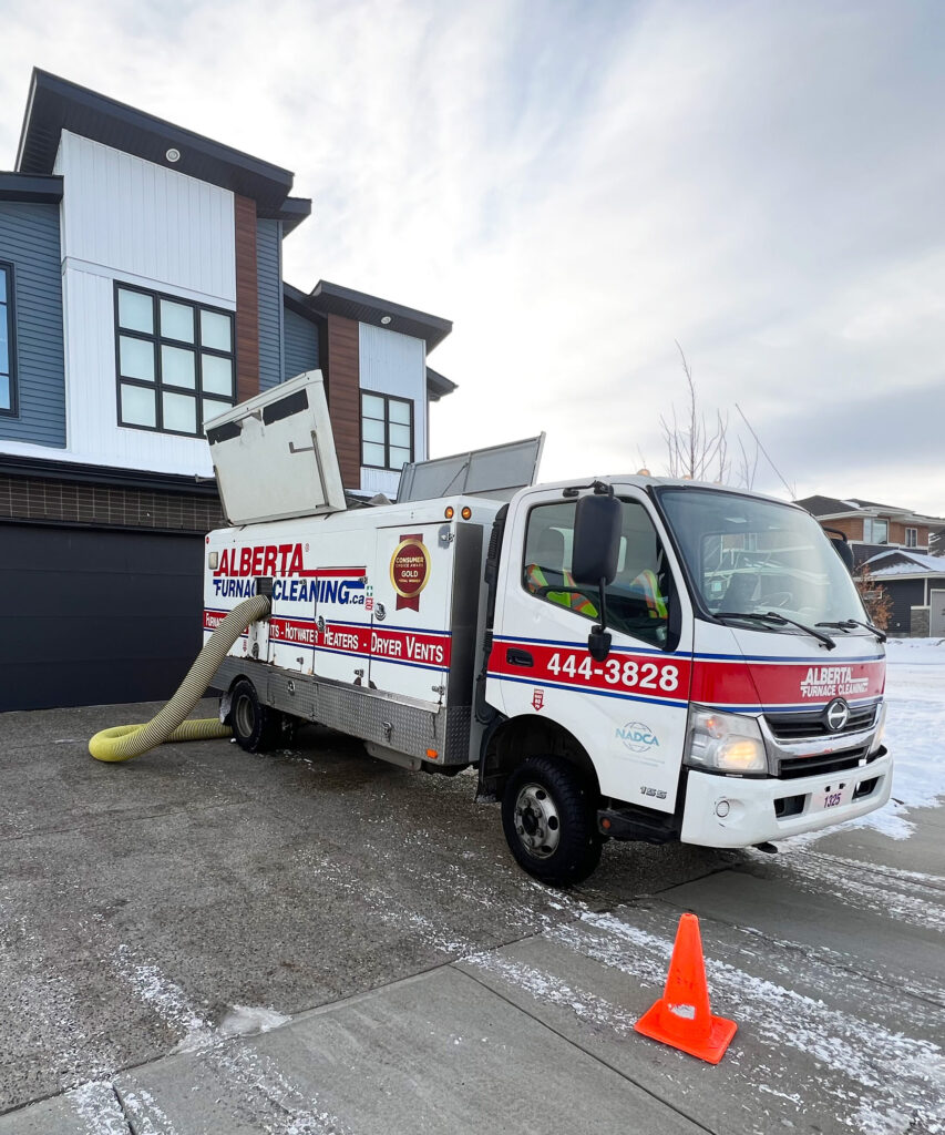 An Alberta Furnace Cleaning truck parked in front of a customers' house in the winter. 