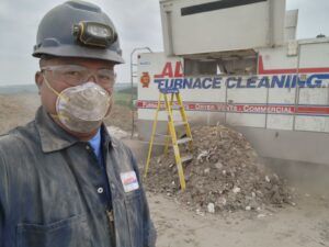 An Alberta Furnace Cleaning technician in front of his furnace cleaning truck, emptying it at an Edmonton dump site. 