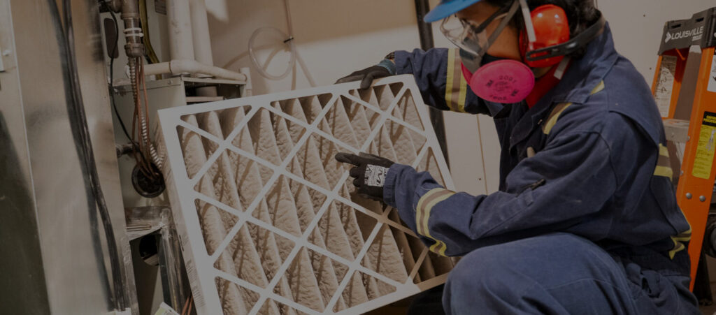 Alberta Furnace Cleaning Technician inspecting a furnace filter during a furnace cleaning. 